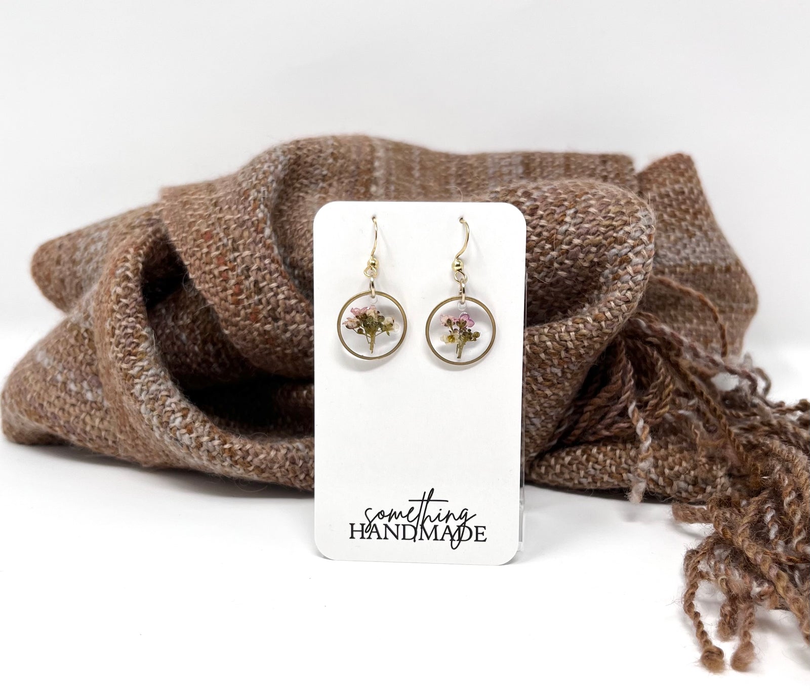 Pair of earrings on a 'something handmade' card with a brown fabric background